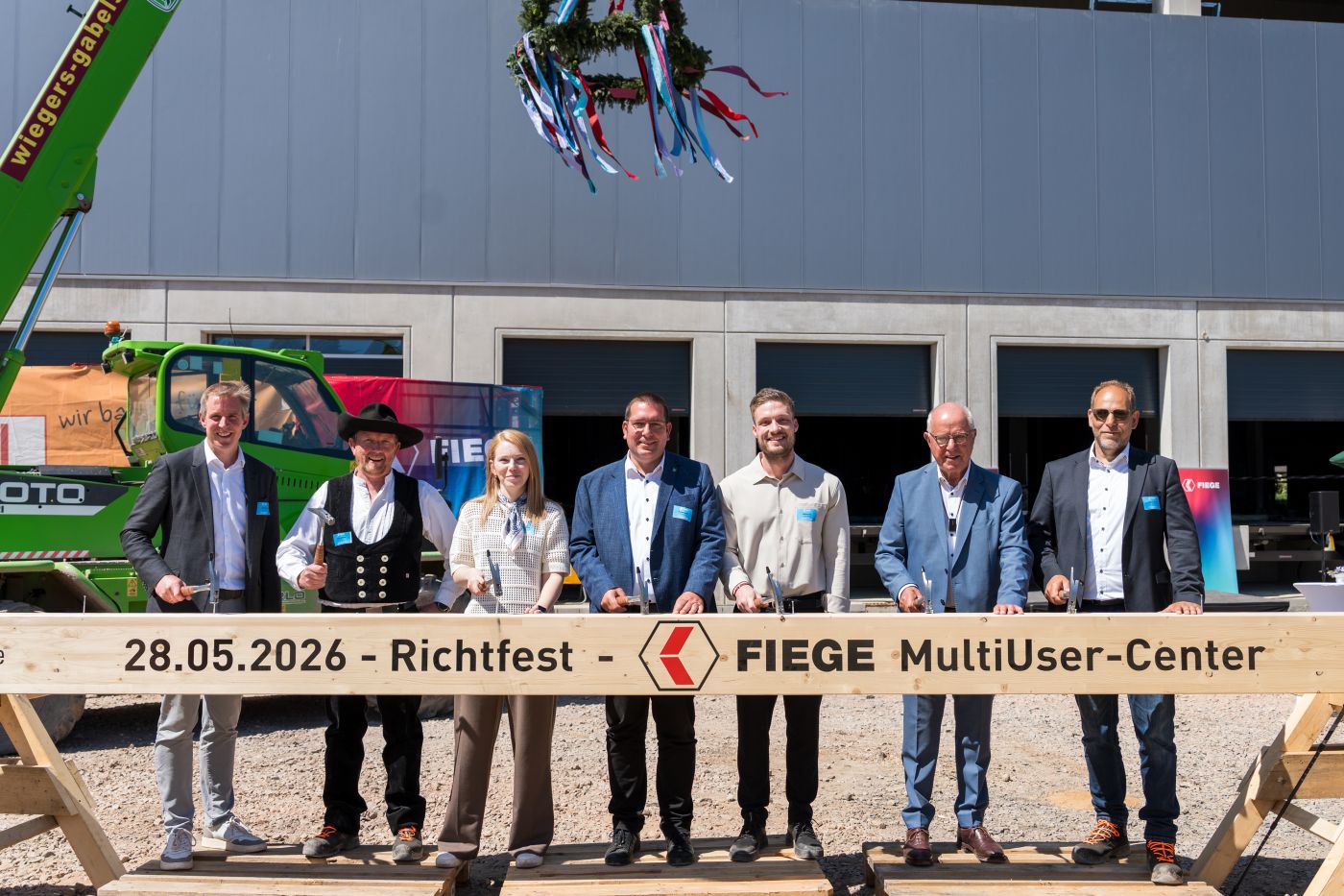 Knocking on wood (from left to right): Jens Fiege (Co-CEO of Fiege), Rene Jüttner (carpenter), Mona Mirek (Fiege Real Estate), Robert Graaf (Mayor of the city of Hamminkeln), Malte Fink (Fiege Real Estate), Heinz Fiege (co-CEO of the fourth generation) and Oliver Aust (Max Bögl) at the topping-out ceremony for the new Fiege logistics centre in Hamminkeln. (Photo: Fiege)